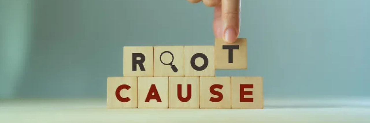 A person stacking wooden blocks that spell out "root cause".